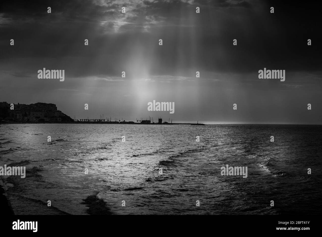 Summer dramatic sky with thunderstorm over the sea off the coast of the Gargano peninsula. In the background the port of Rodi Garganico. Stock Photo