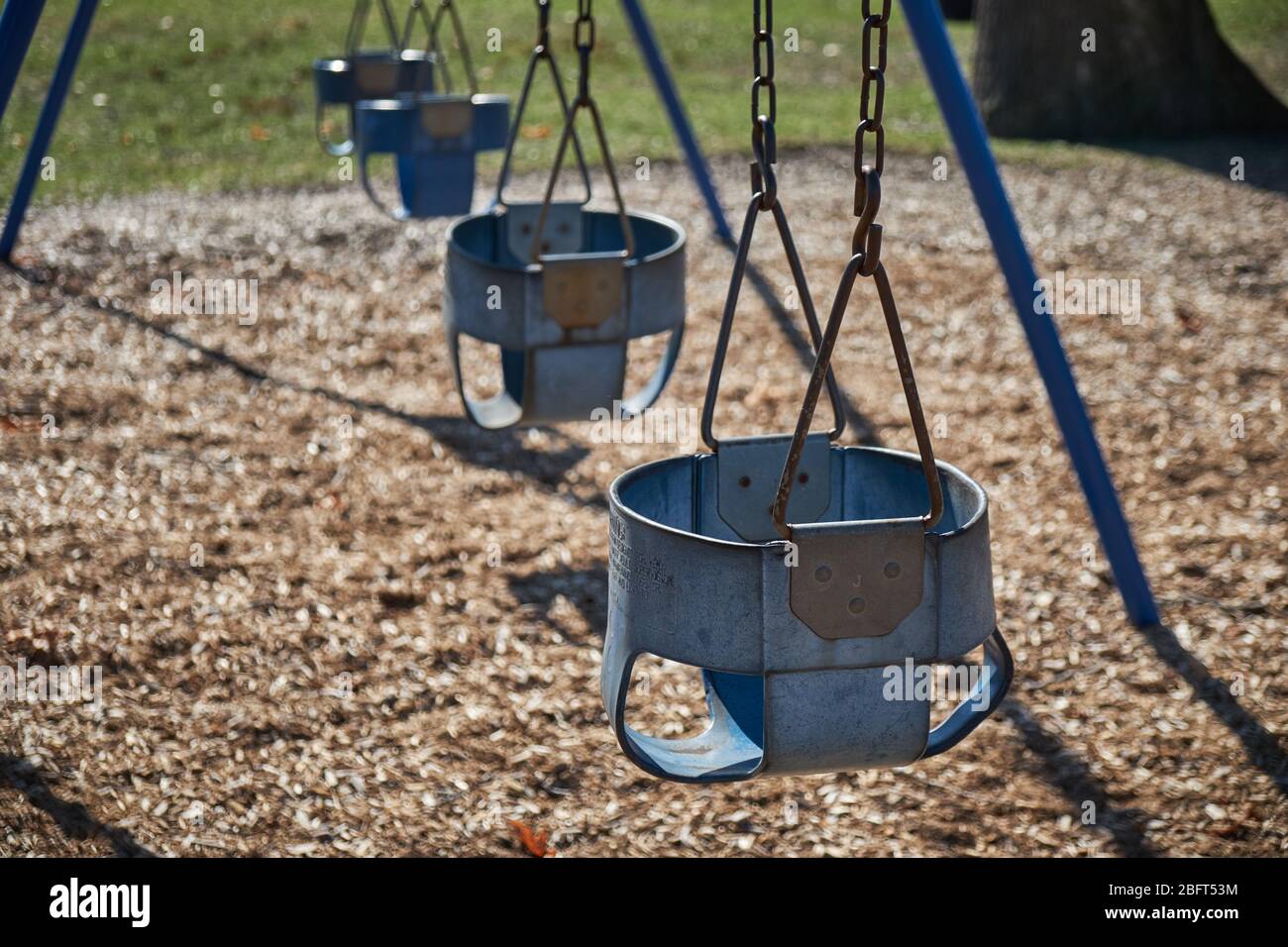 Empty swing sets at a municipal park on a sunny day in Michigan due to COVID 19 quarantine lockdown Stock Photo