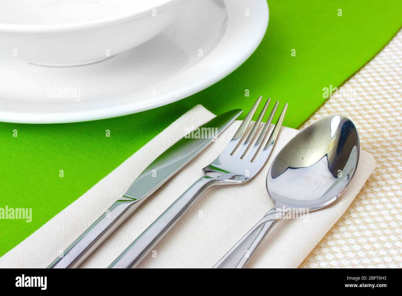 Table setting with fork, knife, spoon, plates, and napkin Stock Photo -  Alamy