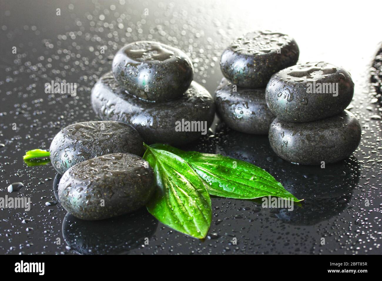 Spa stones with drops and green leaves on grey background Stock Photo ...