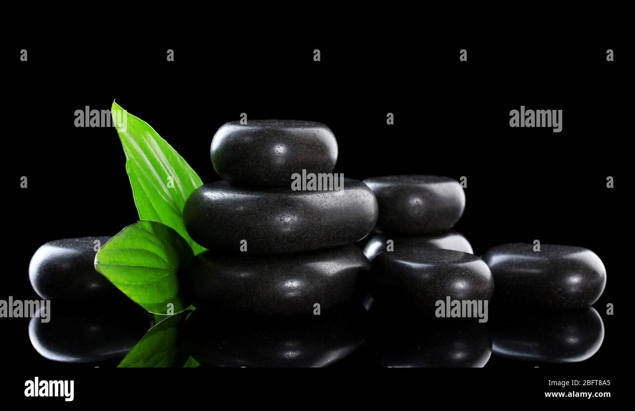 Spa stones and green leaves on black background Stock Photo - Alamy