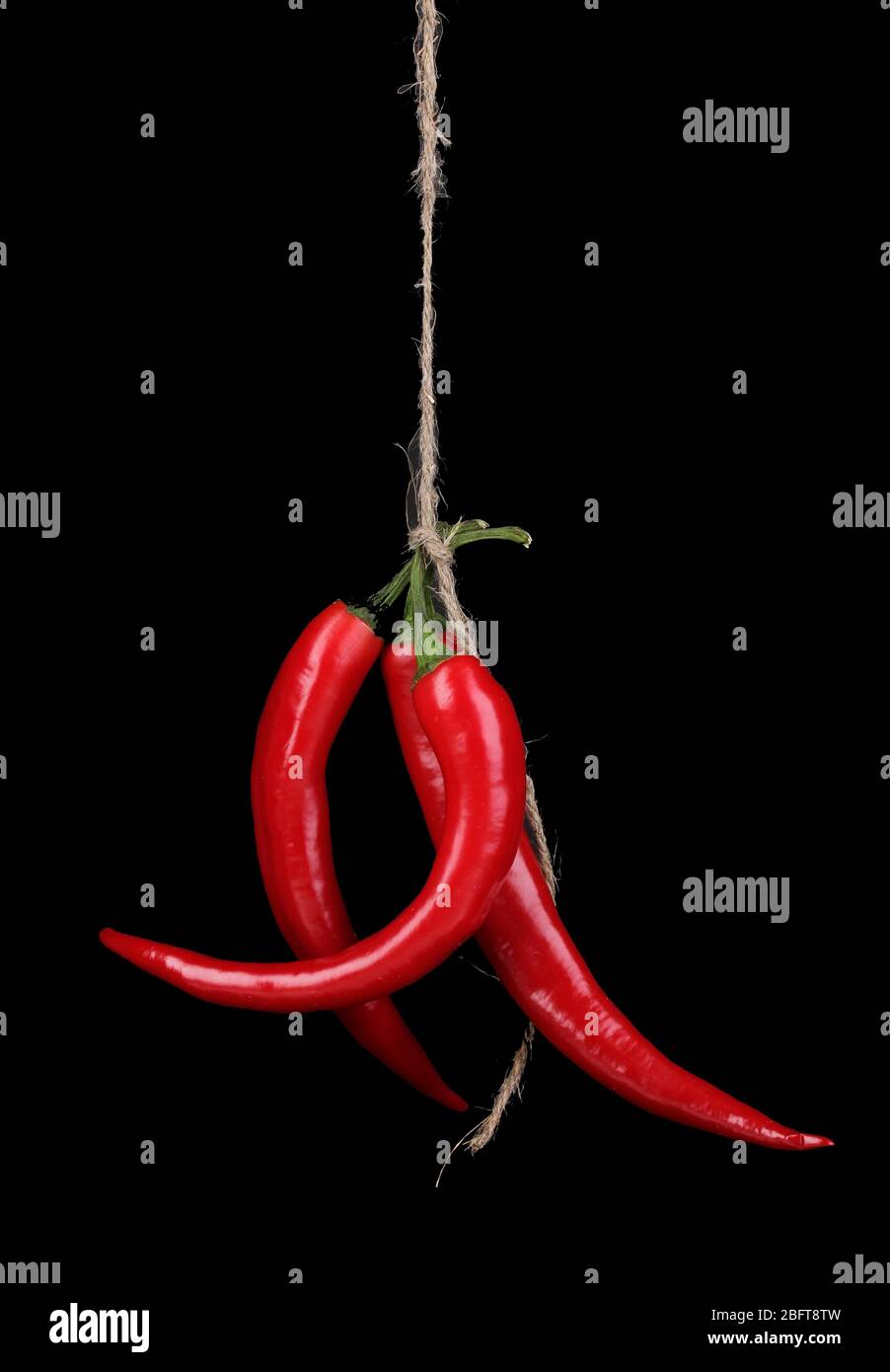 Red hot chili peppers tied with rope isolated on black Stock Photo - Alamy