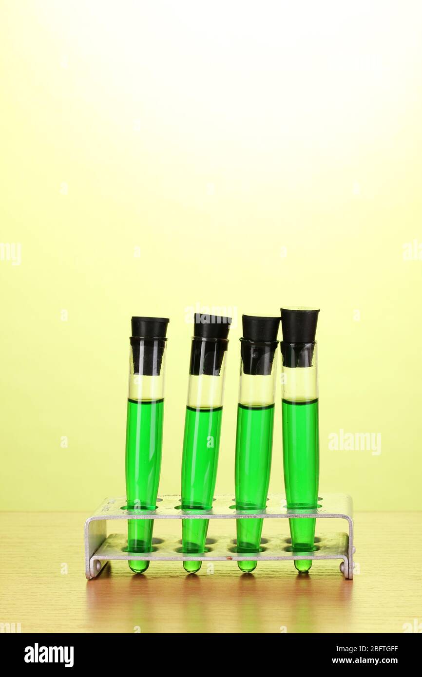 Test-tubes with green liquid on wooden table on green background Stock ...