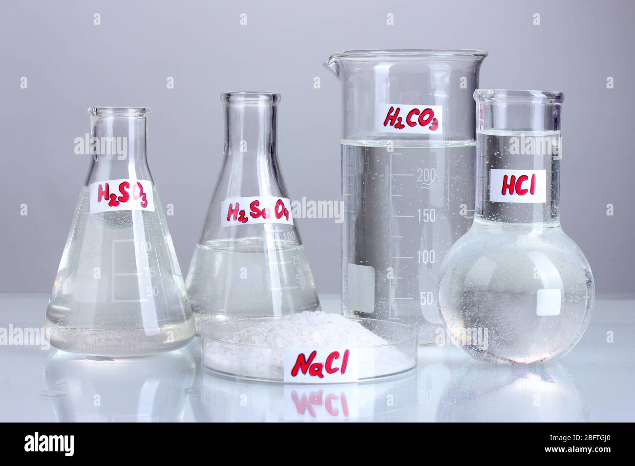 Test-tubes with various acids and chemicals on grey background Stock ...