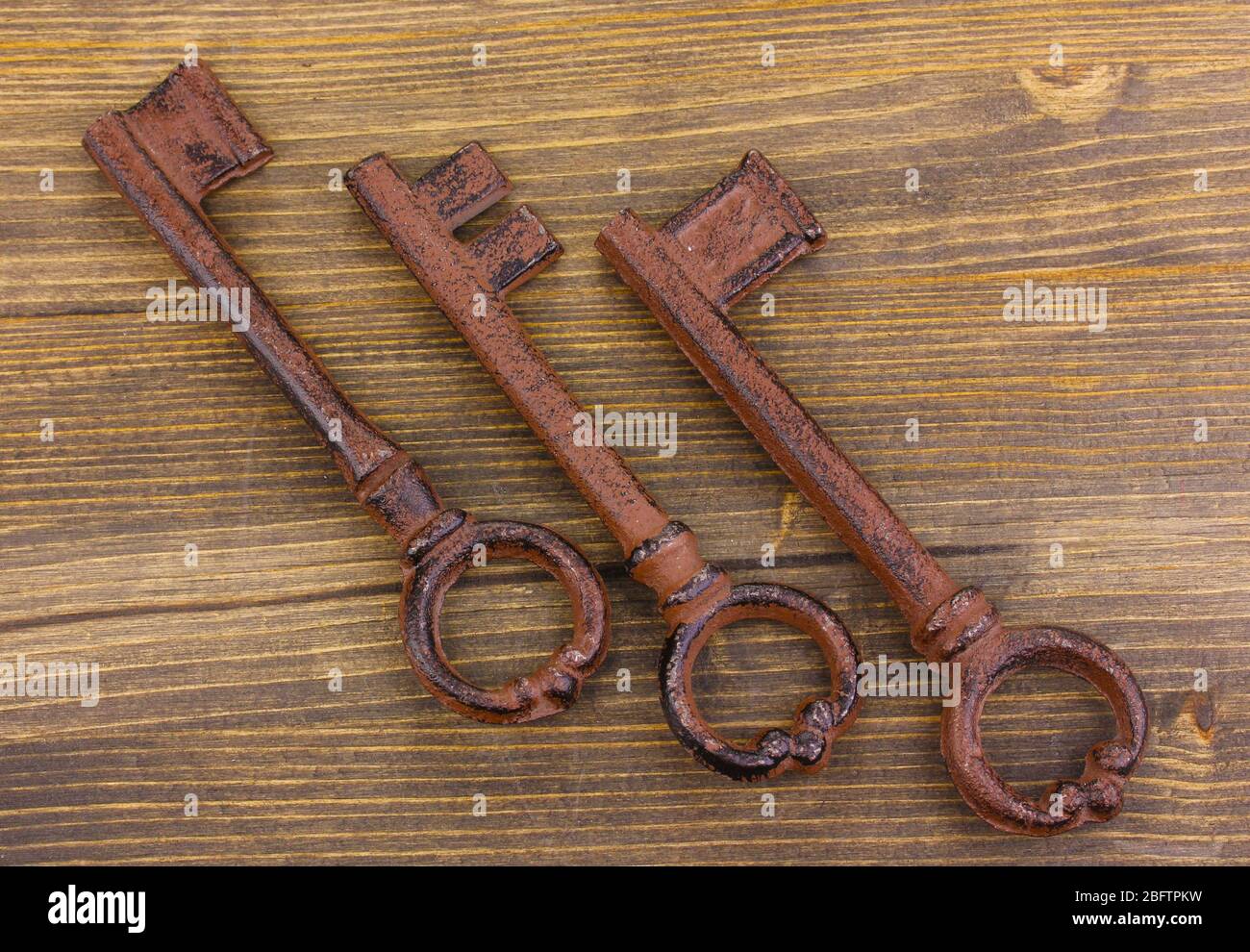 Three antique keys on wooden background Stock Photo