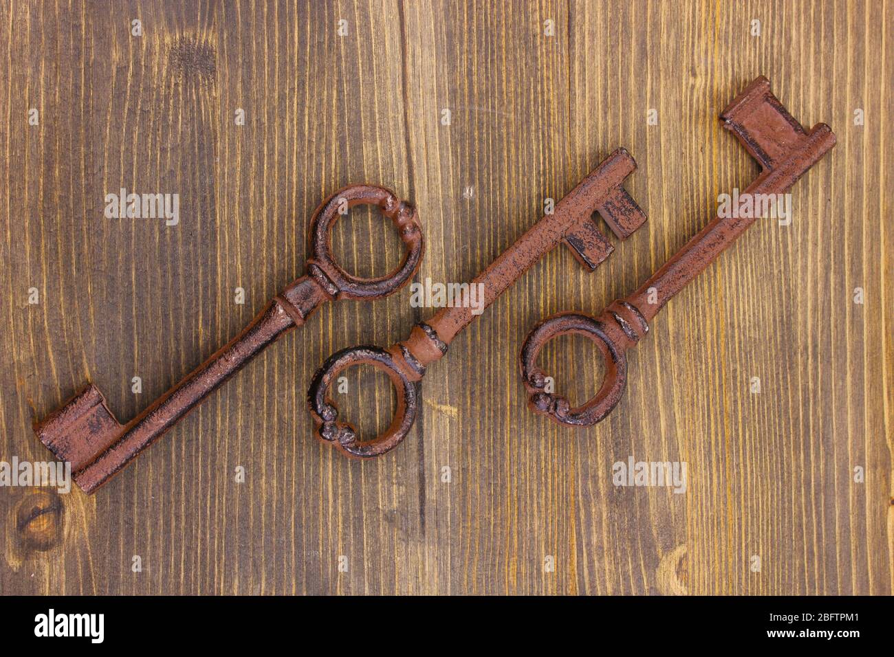 Three antique keys on wooden background Stock Photo