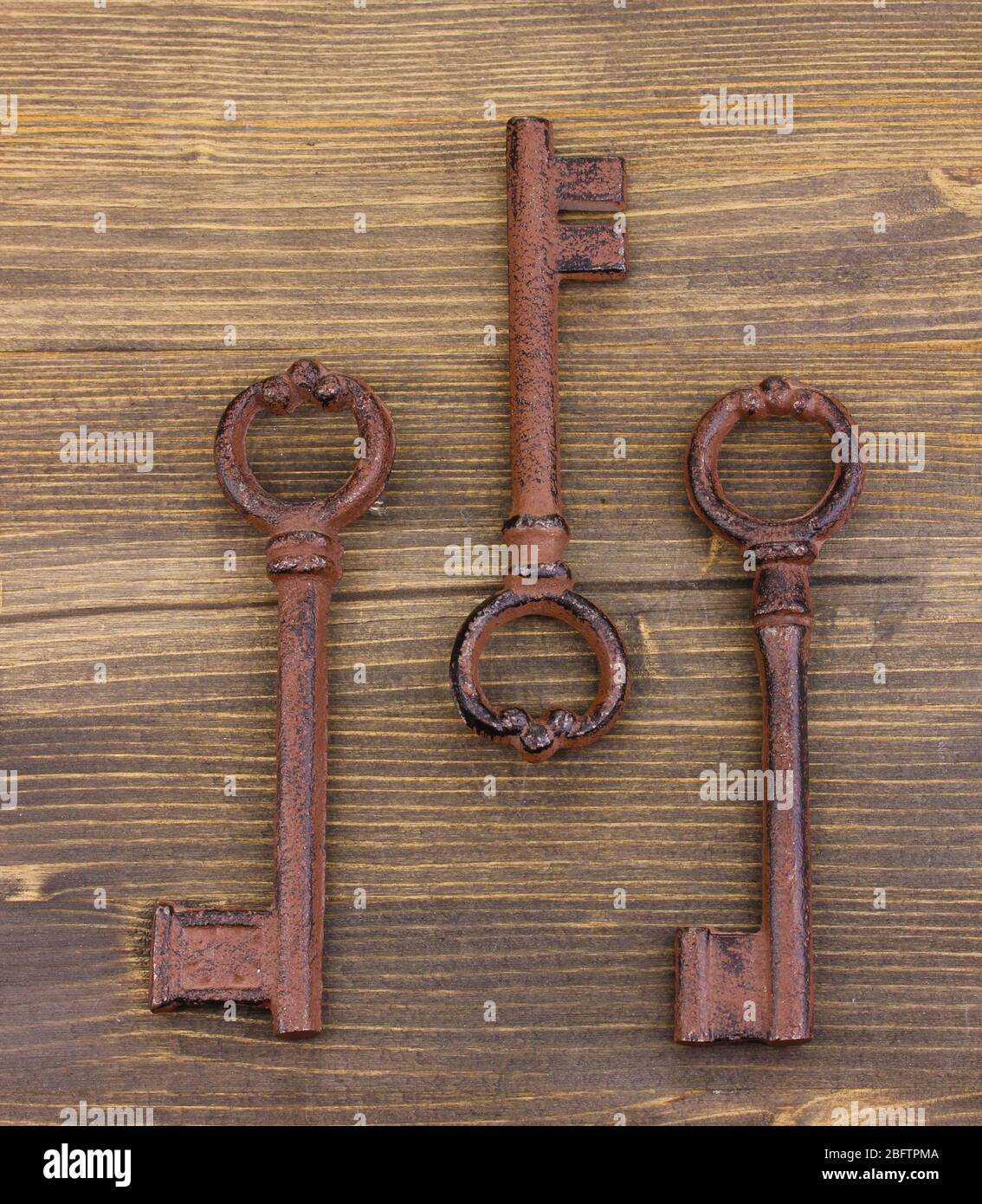Three antique keys on wooden background Stock Photo