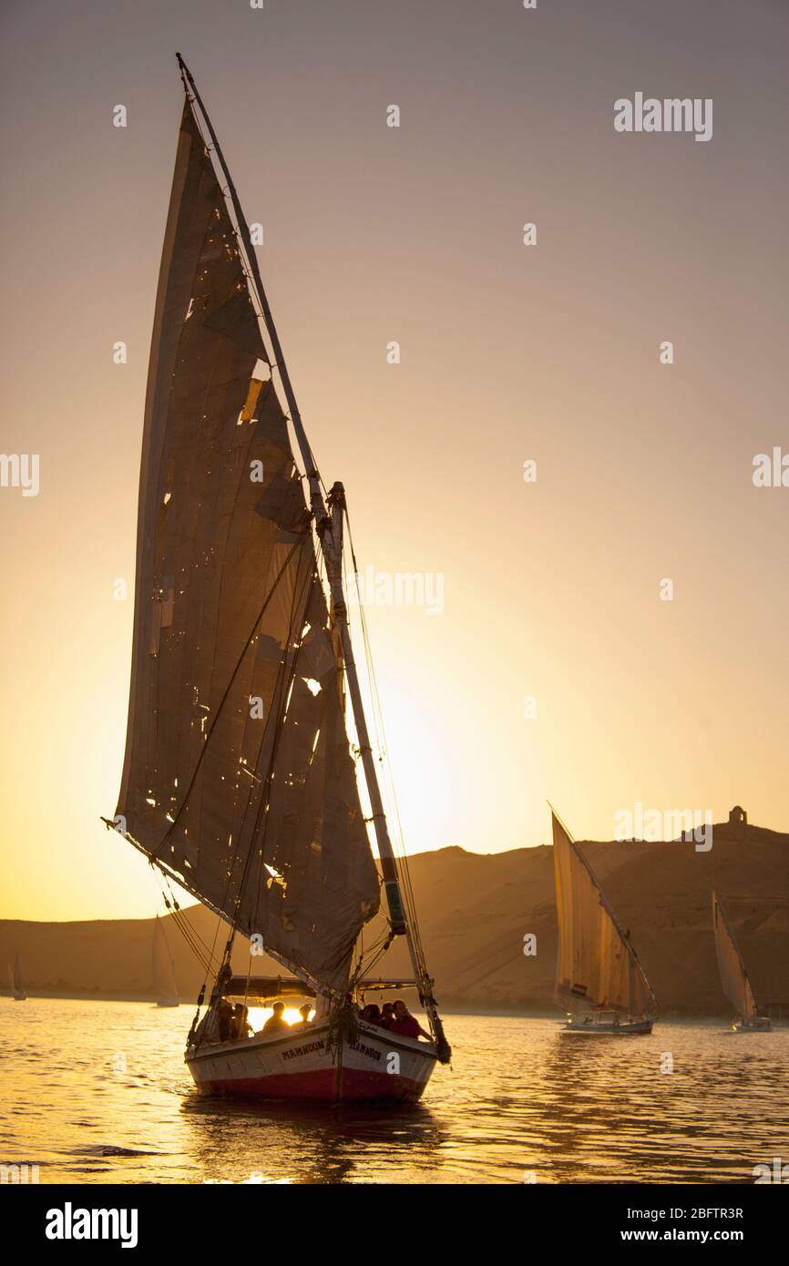 A Felucca Sailboat is silhouetted at Sunset on the Nile River in Aswan, Egypt. Stock Photo