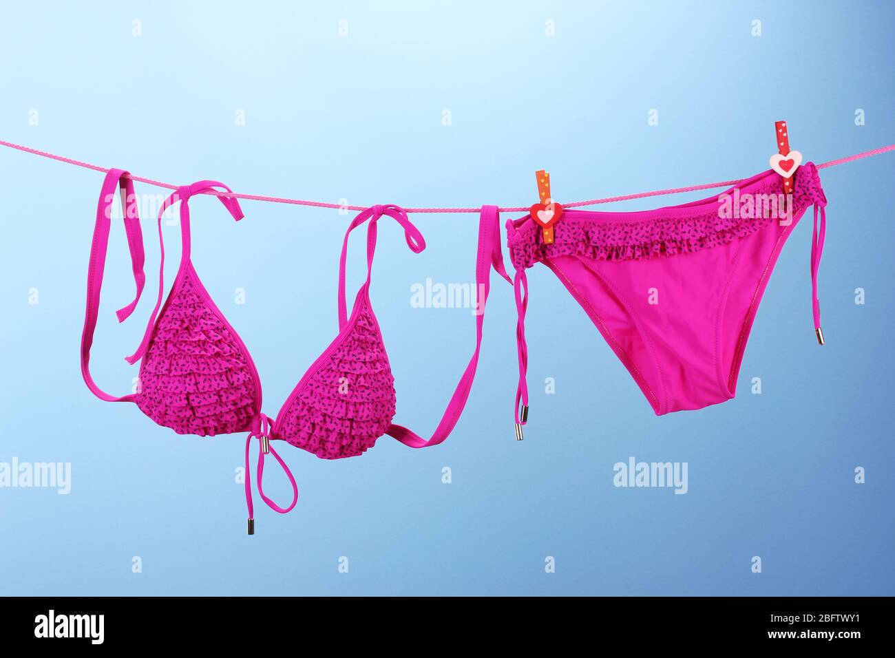 Women's swimsuit hanging on a rope on blue background Stock Photo Alamy