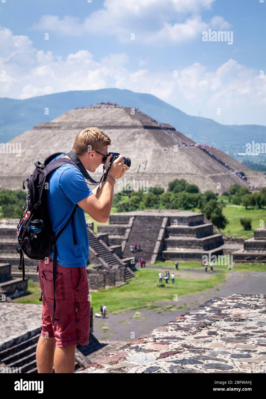 Young man photographs from atop the Pyramid of the Moon in Teotihuacan, Mexico. Stock Photo