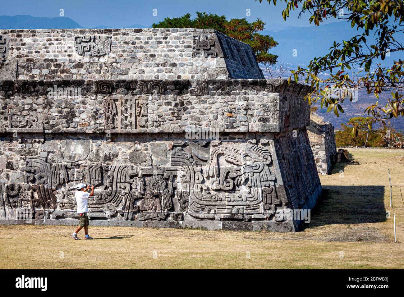 A young man photographs the Pyramid of the Feathered Serpents at the Xochicalco ruins, Morelos, Mexico. Stock Photo