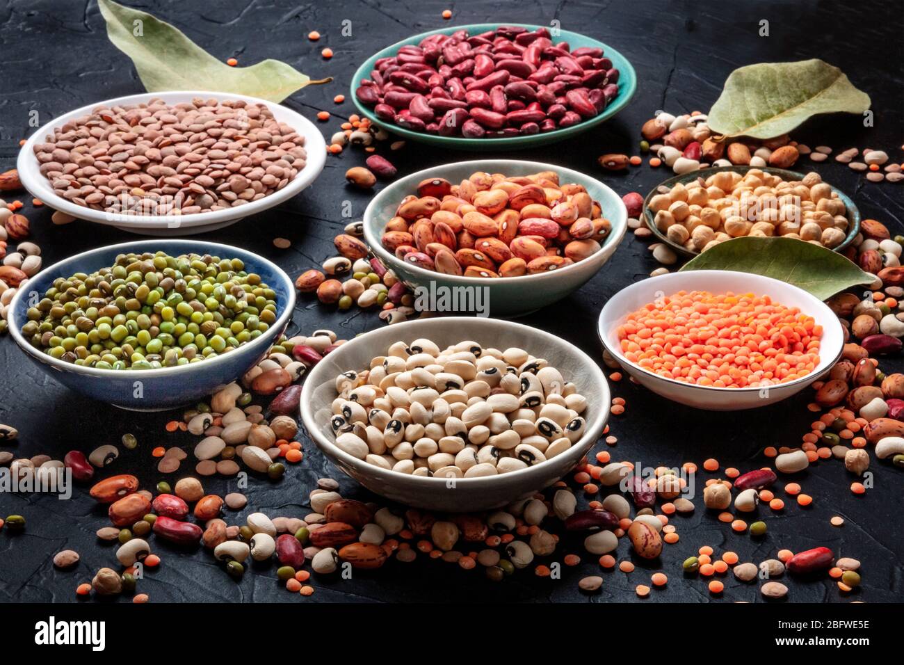 Legumes assortment on a black background. Lentils, soybeans, chickpeas, red kidney beans, a