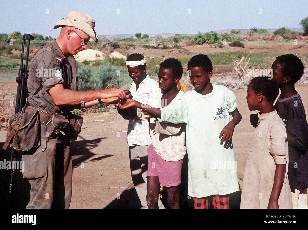 1993 - A German soldier hands out candy to Somali children in Belet Weyne.  The soldier is part of the United Nations contingent supporting OPERATION CONTINUE HOPE. Stock Photo