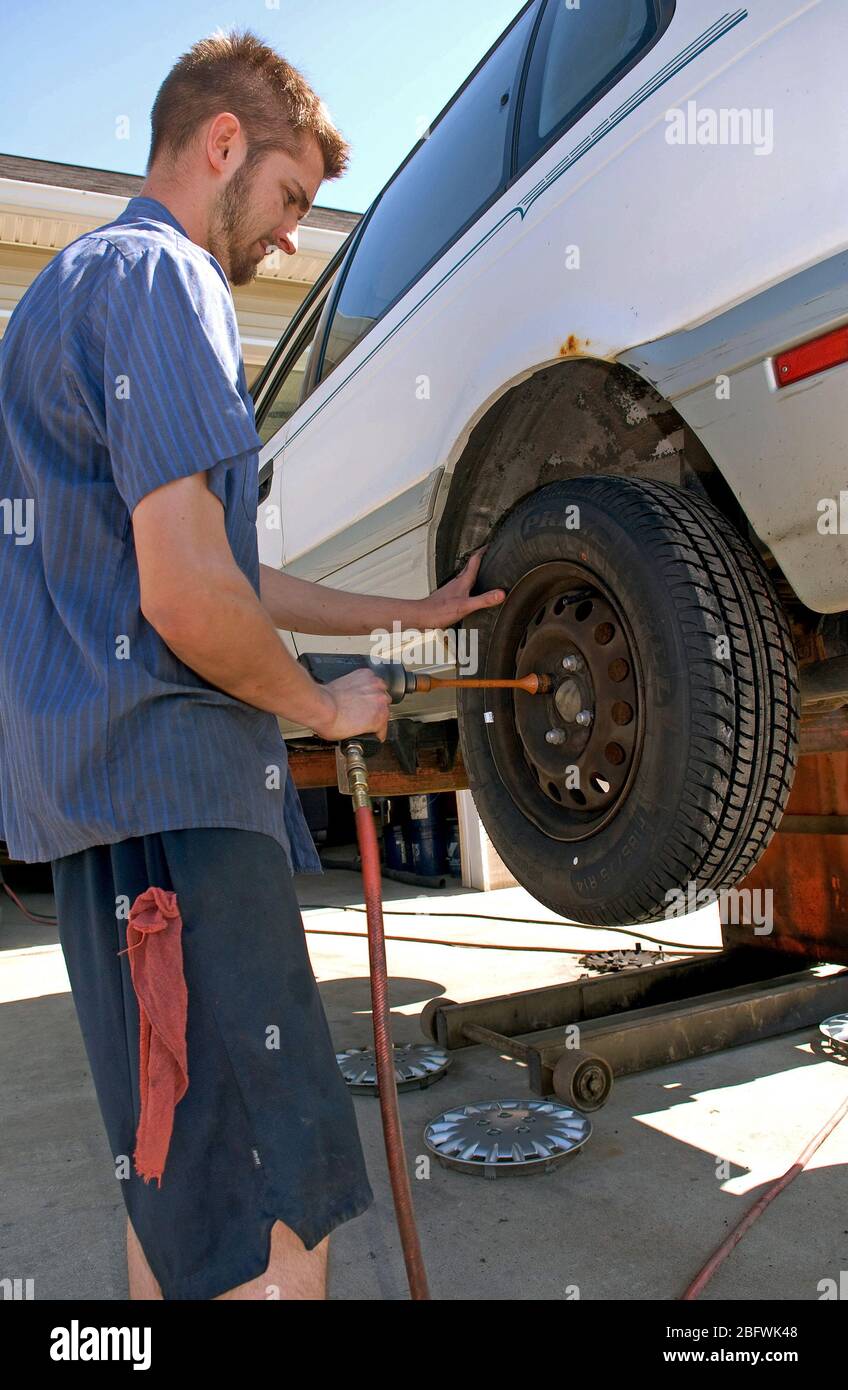 2007 - Mechanic removing lugnuts from the wheel of a car on a lift Stock Photo