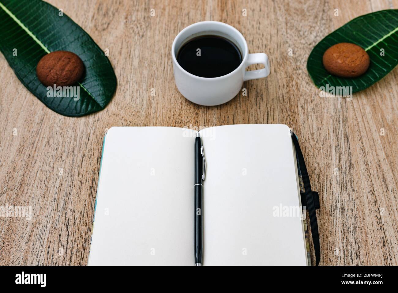 Flat lay, open blank U-turn of a notepad with white paper, morning recording of plans, breakfast with aromatic coffee and chocolate chip cookies. Comp Stock Photo