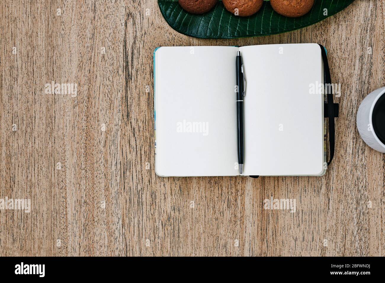 Flat lay, open blank U-turn of a notepad with white paper, morning recording of plans, breakfast with aromatic coffee and chocolate chip cookies. Comp Stock Photo