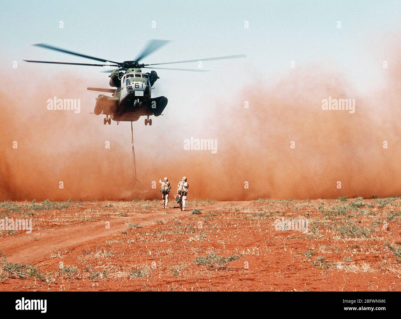 A Marine Heavy Helicopter Squadron 363 (HMH-363) CH-53D Sea Stallion helicopter delivers a load of grain to a field outside the village of Maleel during the multinational relief effort OPERATION RESTORE HOPE.  The grain, donated by Australia, is being flown in instead of driven because it is suspected that the roads lading to the village have been mined. Stock Photo