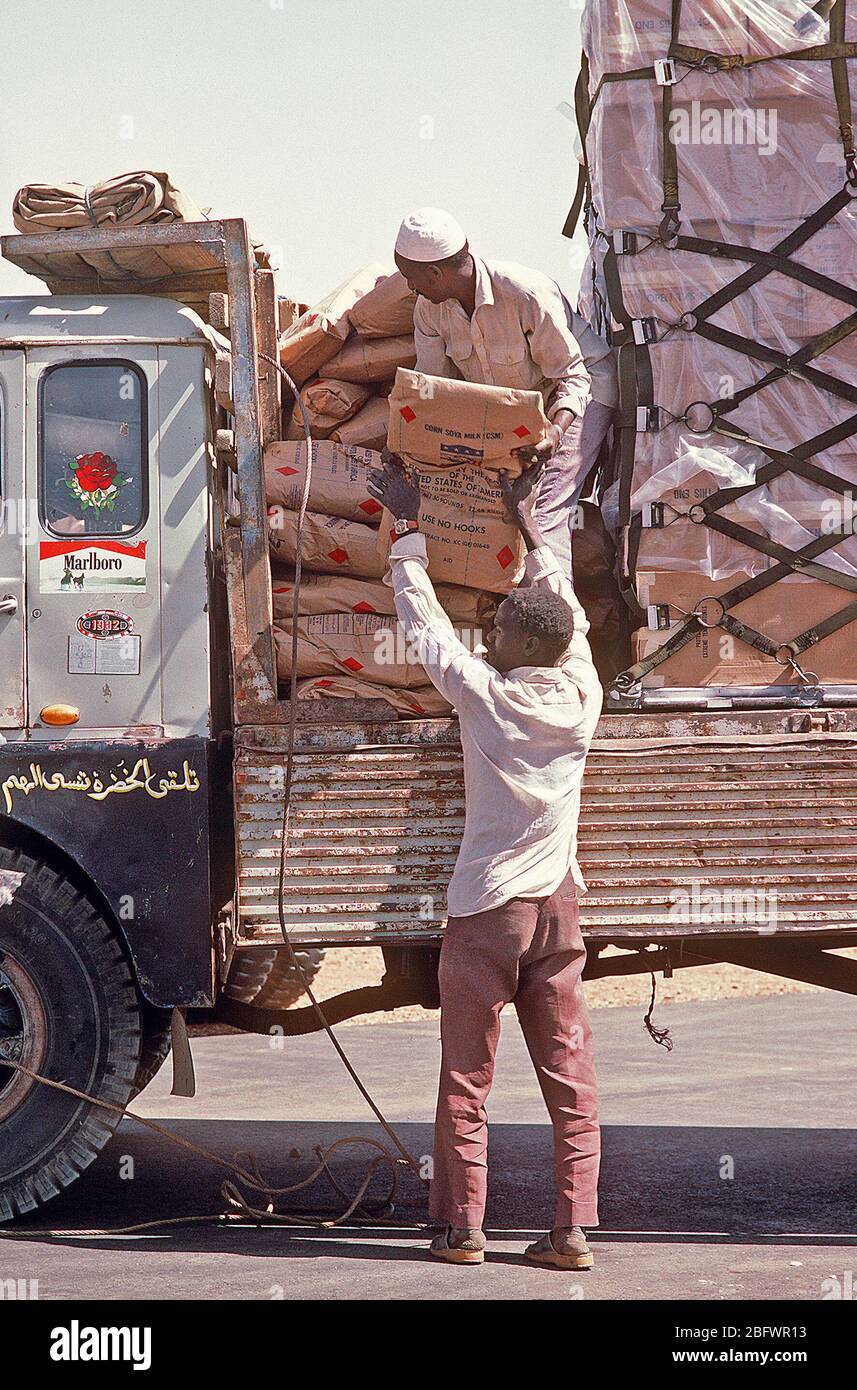 1985 - Two Sudanese workers load a truck with food and supplies that were flown into the airport aboard a 6th Military Airlift Squadron aircraft during Ethiopian relief operations.  The supplies will be moved to a distribution center and given to the needy. Stock Photo