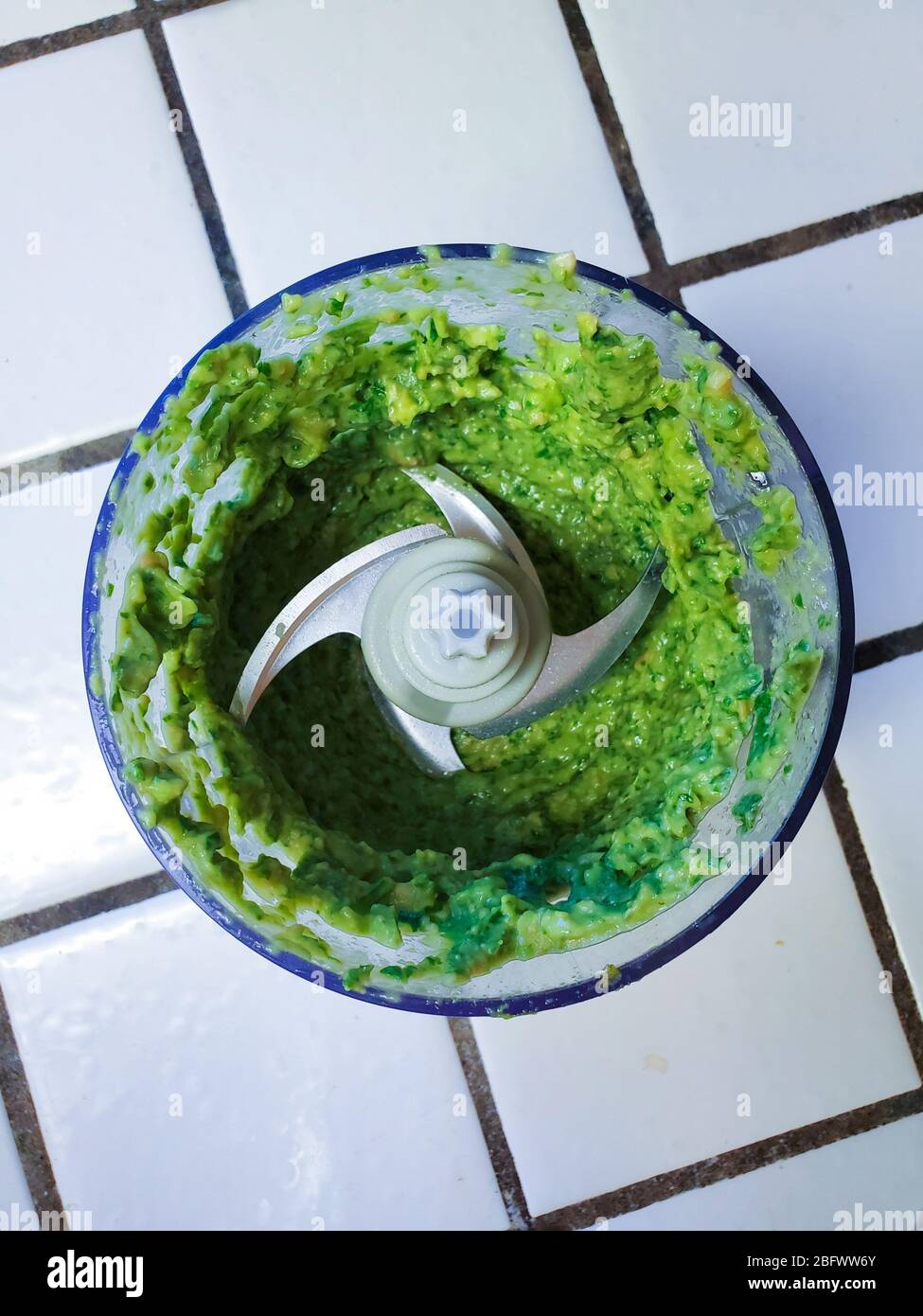 Organic avocado basil pesto in a food processor on a kitchen counter