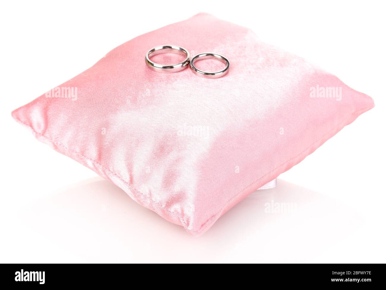 Wedding rings on satin pillow isolated on white Stock Photo