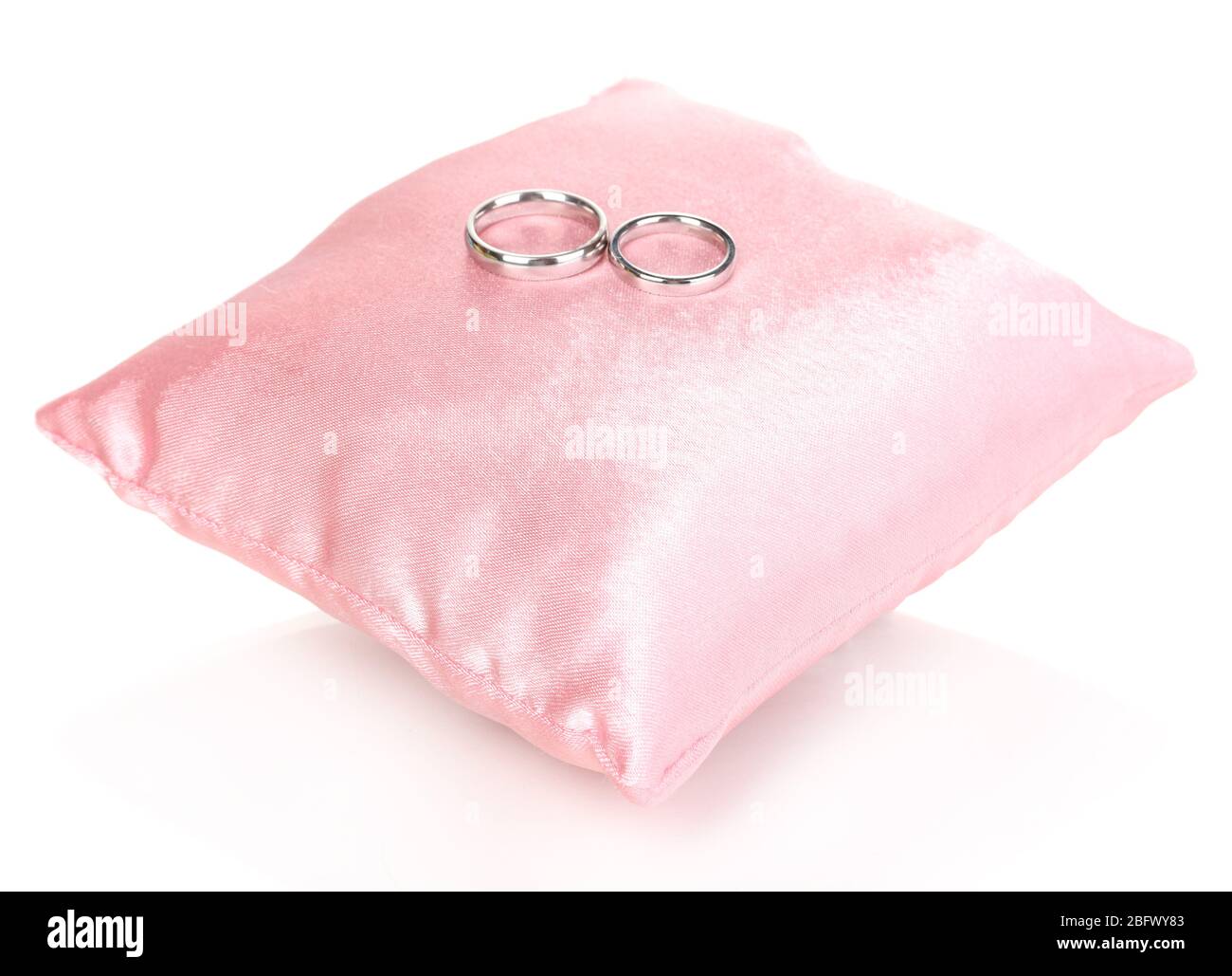 Wedding rings on satin pillow isolated on white Stock Photo