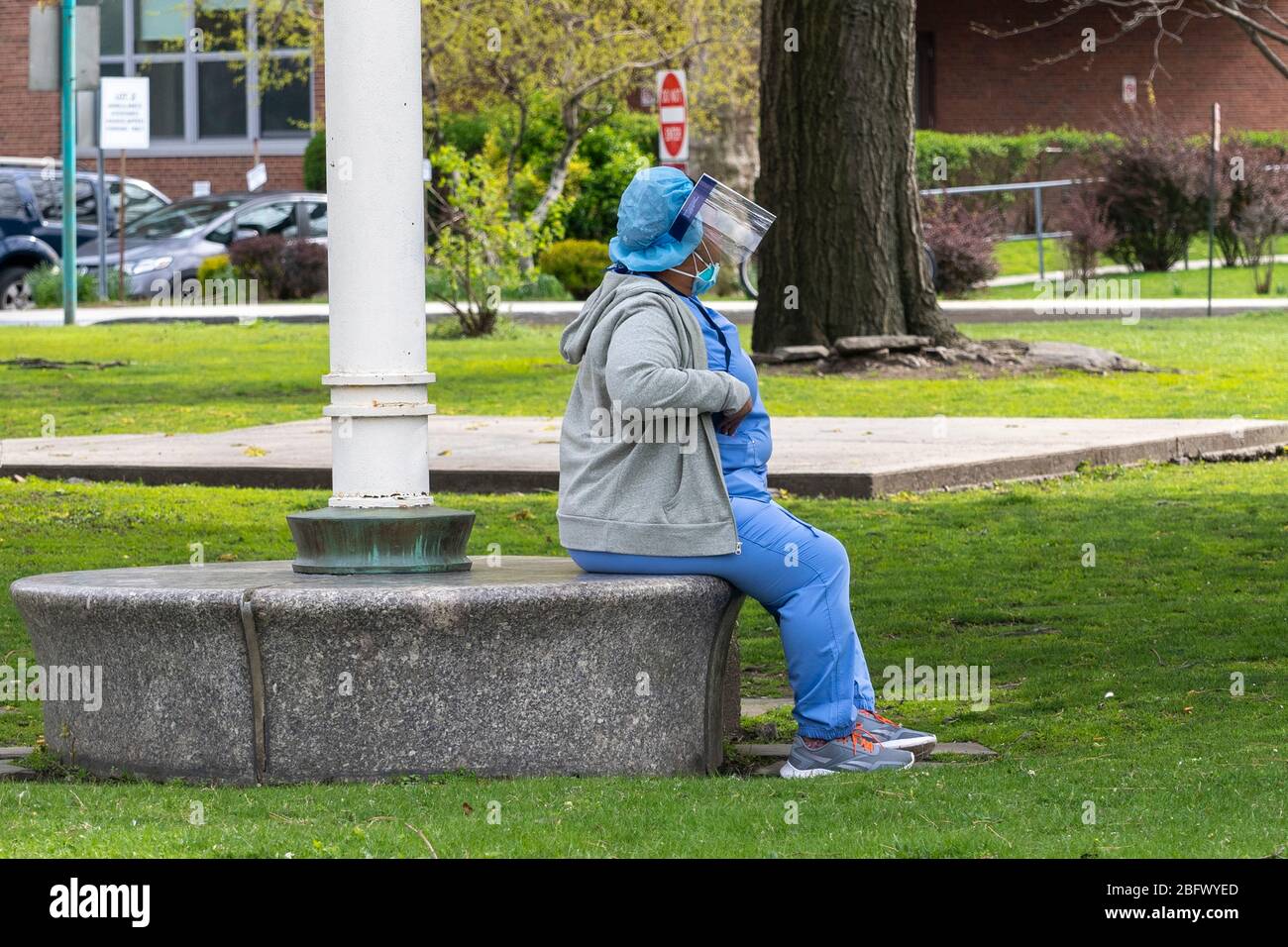 New York, United States. 19th Apr, 2020. A nurse wearing a personal protective equipment (PPE) takes a break outside the Coler Hospital campus at Roosevelt Island amid the coronavirus (covid-19) pandemic in New York City. Coler Hospital, which was closed in 2018, is being looked at by New York City as a location to expand hospital facilities to treat coronavirus patients. Credit: SOPA Images Limited/Alamy Live News Stock Photo