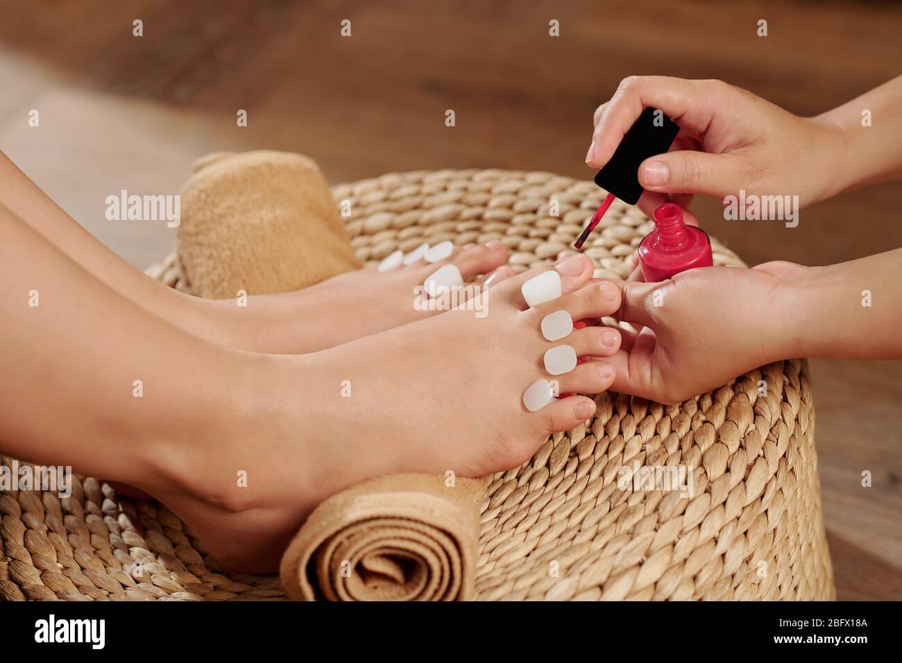 Process of applying bright red nail polish on toenails in beauty salon