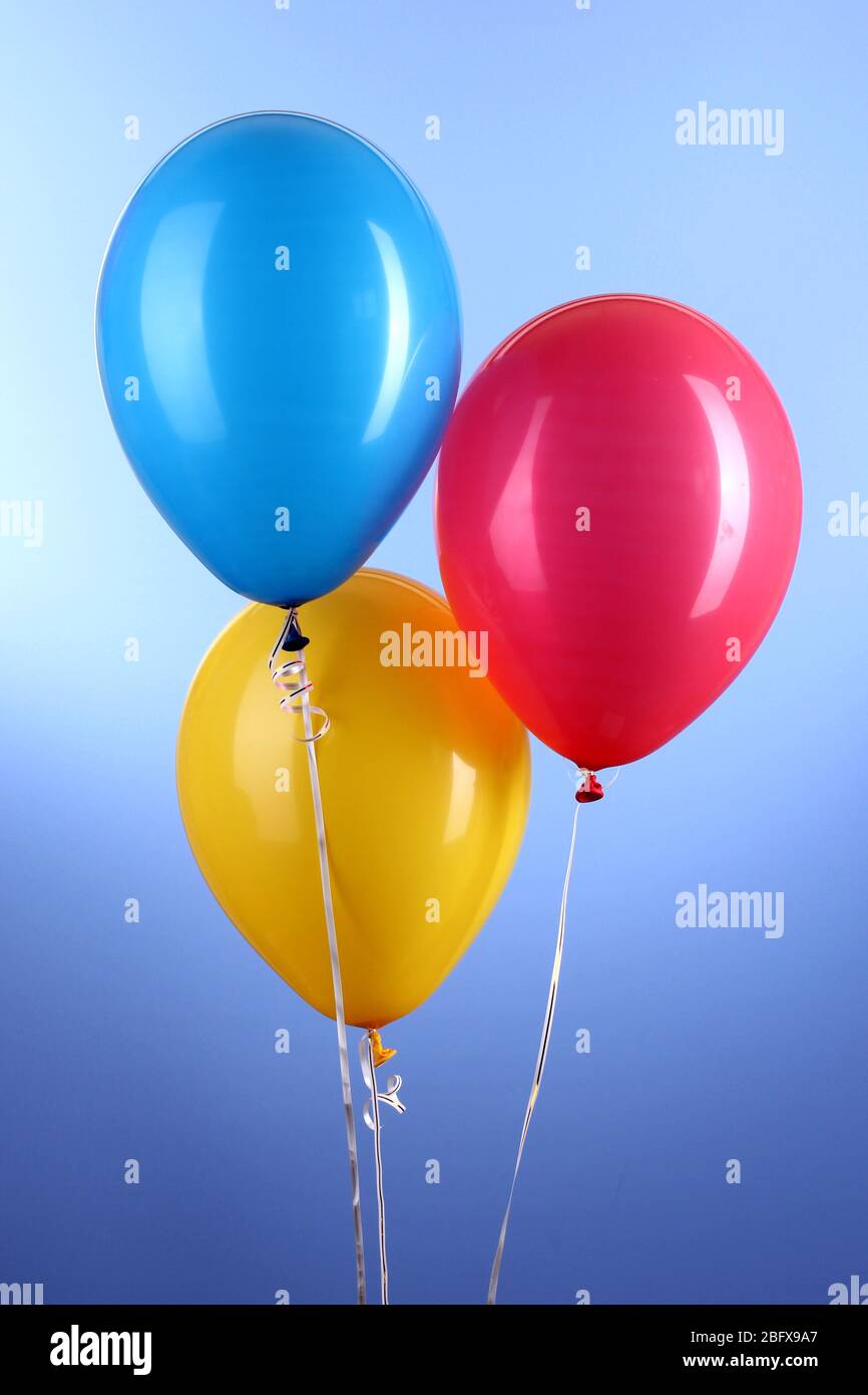 Three colorful balloons on blue background Stock Photo - Alamy