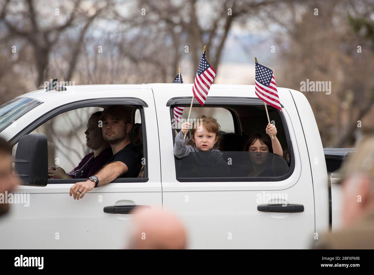 Helena, Montana - April 19, 2020: Children girls holding and waving American flag from a vehicle at the protest at the Capitol to reopen business and Stock Photo