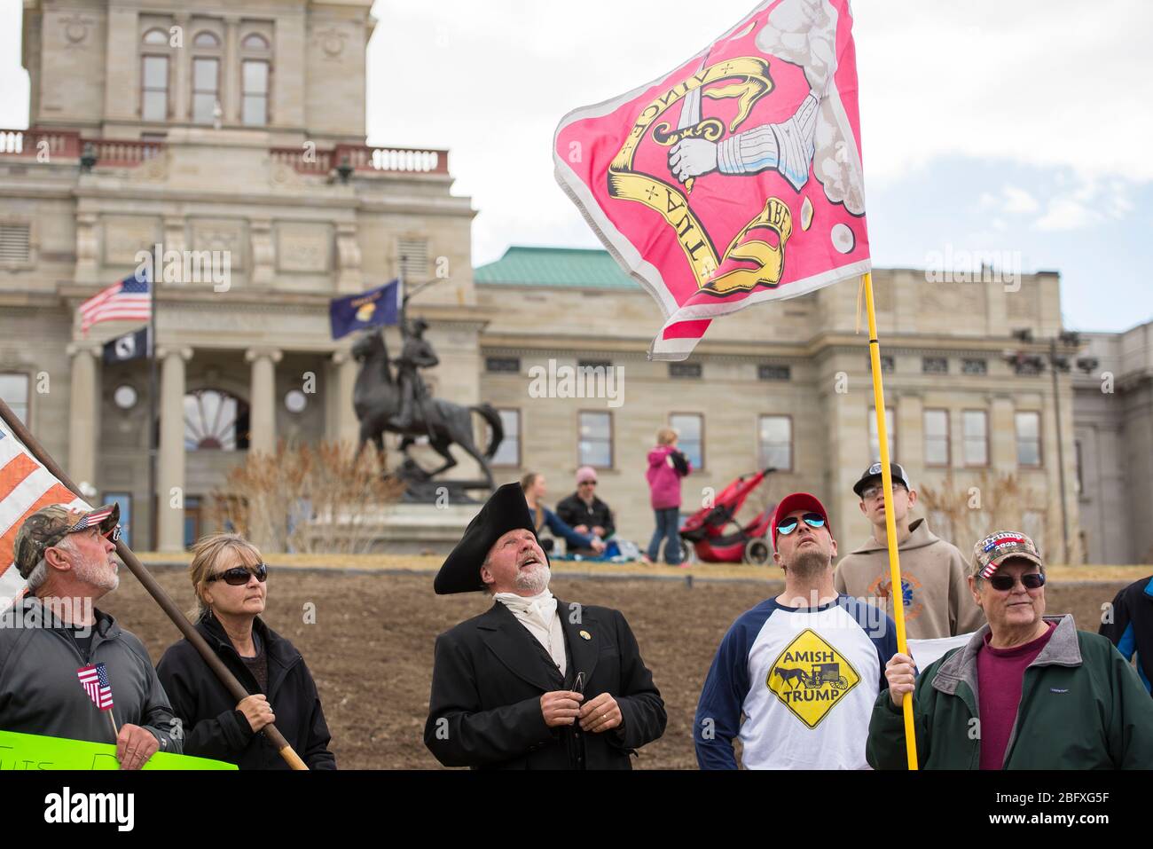 Helena, Montana - April 19, 2020: Protestors hold American flags and looking up at the Bedford Militia Flag at a rally wanting to reopen business due Stock Photo