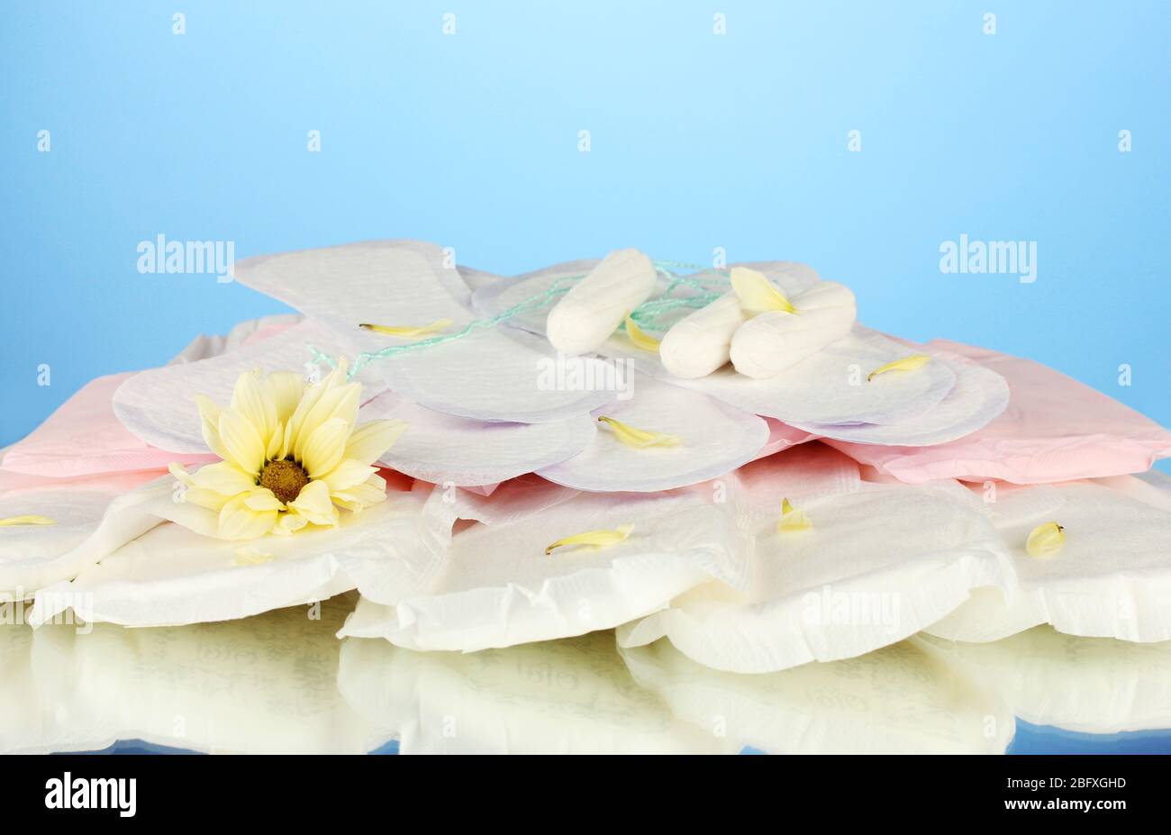 various types of sanitary pads and tampons on blue background closeup