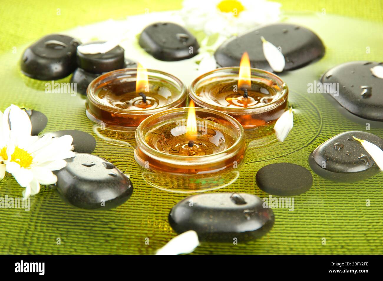 spa stones with flowers and candles in water on plate Stock Photo - Alamy