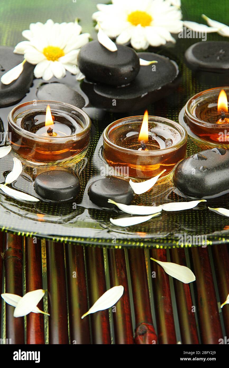 spa stones with flowers and candles in water on plate Stock Photo - Alamy