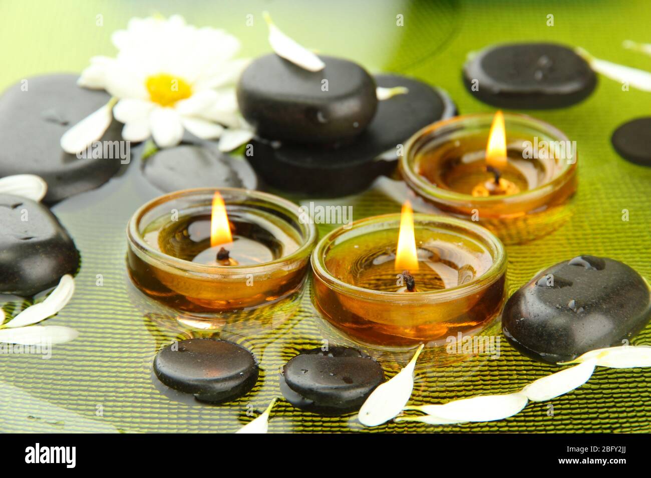 spa stones with flowers and candles in water on plate Stock Photo - Alamy