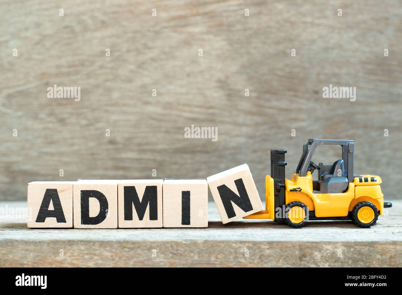 Toy forklift hold letter block n to complete word admin on wood background Stock Photo