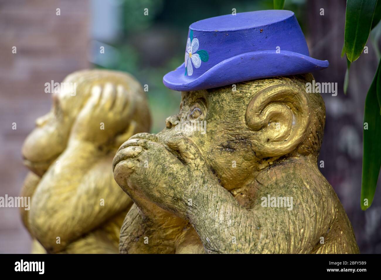 The figurine of Three wise monkeys at garden of Buddhist temple, Nakhon Nayok, Thailand.A statue of Iwazaru, covering his mouth, who speaks no evil. Stock Photo