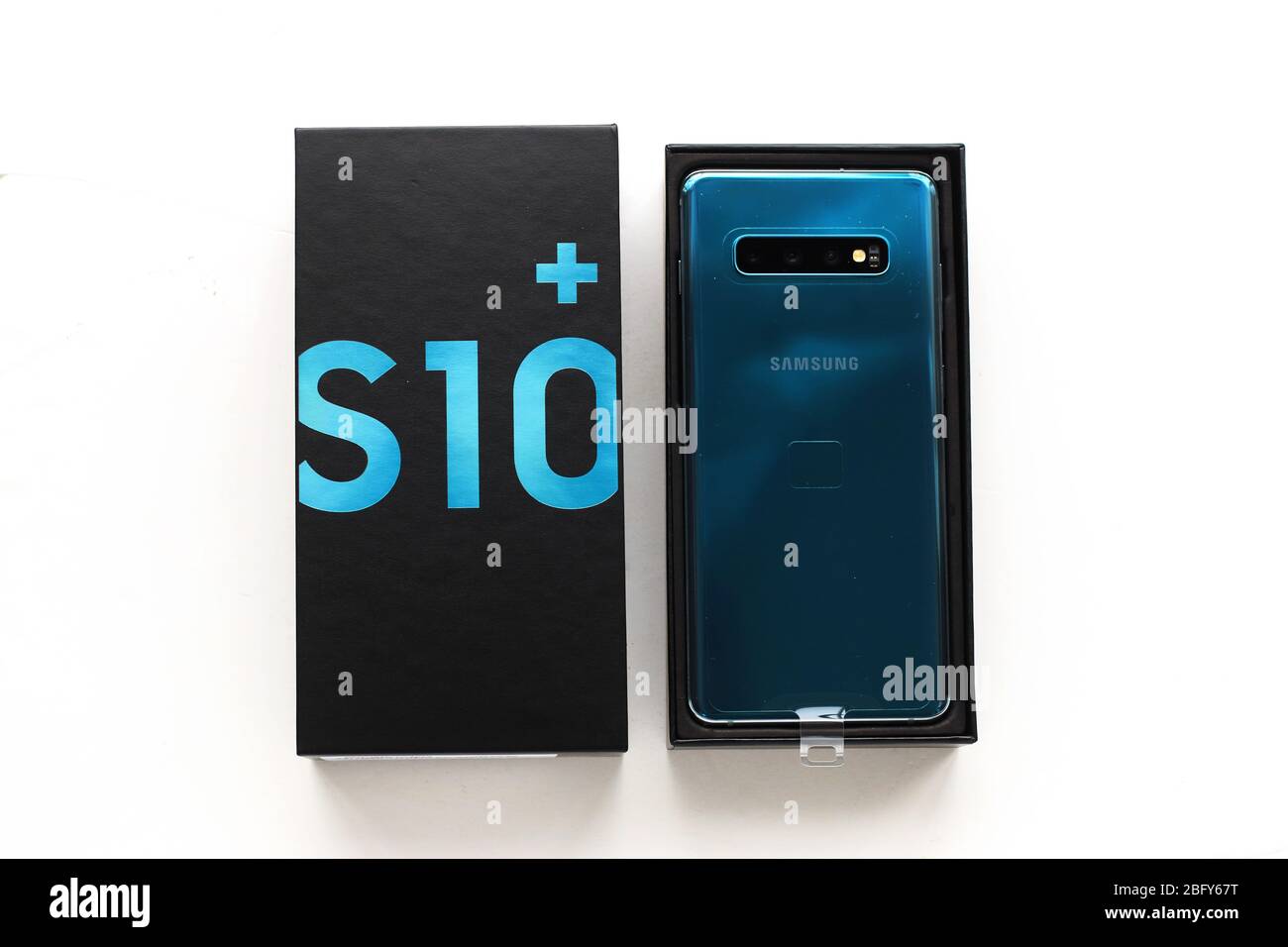 Hand holding Samsung Galaxy S10+ smart phone isolated against white background Stock Photo