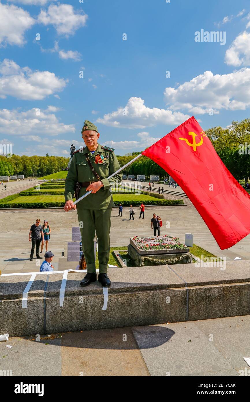 May 9, 2016, Berlin, at the Soviet War Memorial in Treptower Park (Treptower War Memorial), a memorial and at the same time a military cemetery, numerous Russians and German-Russians with many colorful flags commemorate the 71st day of victory at the end of the Second World War. The memorial was erected in Germany in 1949 on the instructions of the Soviet military administration to honor the soldiers of the Red Army who died in World War II. Over 7000 of the soldiers who died in the Schlaughs around Berlin are buried here. An older man in historical uniform poses with the Soviet flag. | usage Stock Photo