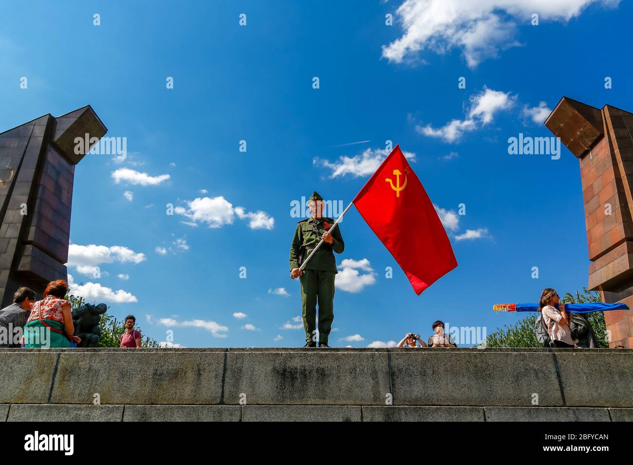 May 9, 2016, Berlin, at the Soviet War Memorial in Treptower Park (Treptower War Memorial), a memorial and at the same time a military cemetery, numerous Russians and German-Russians with many colorful flags commemorate the 71st day of victory at the end of the Second World War. The memorial was erected in Germany in 1949 on the instructions of the Soviet military administration to honor the soldiers of the Red Army who died in World War II. Over 7000 of the soldiers who died in the Schlaughs around Berlin are buried here. An older man in historical uniform poses with the Soviet flag. | usage Stock Photo