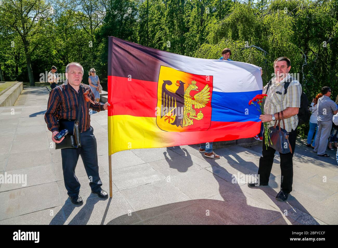 May 9, 2016, Berlin, at the Soviet War Memorial in Treptower Park (Treptower War Memorial), a memorial and at the same time a military cemetery, numerous Russians and German-Russians with many colorful flags commemorate the 71st day of victory at the end of the Second World War. The memorial was erected in Germany in 1949 on the instructions of the Soviet military administration to honor the soldiers of the Red Army who died in World War II. Over 7000 of the soldiers who died in the Schlaughs around Berlin are buried here. Visitors with a flag that half represents the national flag of the Fede Stock Photo