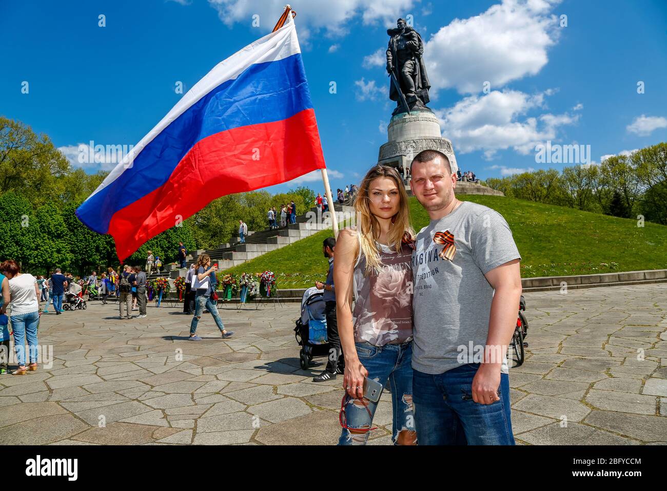 May 9, 2016, Berlin, at the Soviet War Memorial in Treptower Park (Treptower War Memorial), a memorial and at the same time a military cemetery, numerous Russians and German-Russians with many colorful flags commemorate the 71st day of victory at the end of the Second World War. The memorial was erected in Germany in 1949 on the instructions of the Soviet military administration to honor the soldiers of the Red Army who died in World War II. Over 7000 of the soldiers who died in the Schlaughs around Berlin are buried here. A couple poses with the Russian flag. | usage worldwide Stock Photo