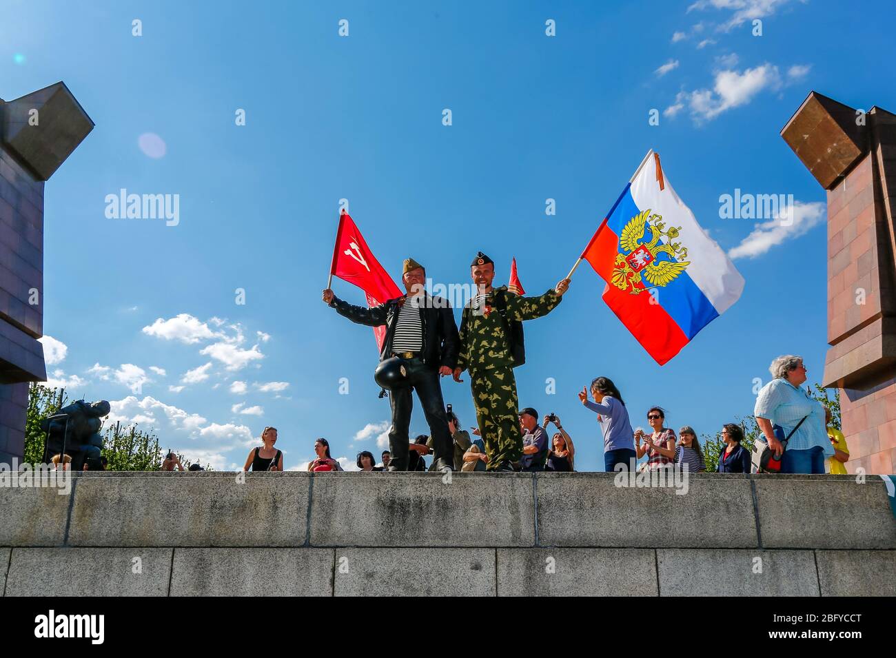 May 9, 2016, Berlin, at the Soviet War Memorial in Treptower Park (Treptower War Memorial), a memorial and at the same time a military cemetery, numerous Russians and German-Russians with many colorful flags commemorate the 71st day of victory at the end of the Second World War. The memorial was erected in Germany in 1949 on the instructions of the Soviet military administration to honor the soldiers of the Red Army who died in World War II. Over 7000 of the soldiers who died in the Schlaughs around Berlin are buried here. Men, some in uniform, pose with the Russian and Soviet national flags. Stock Photo