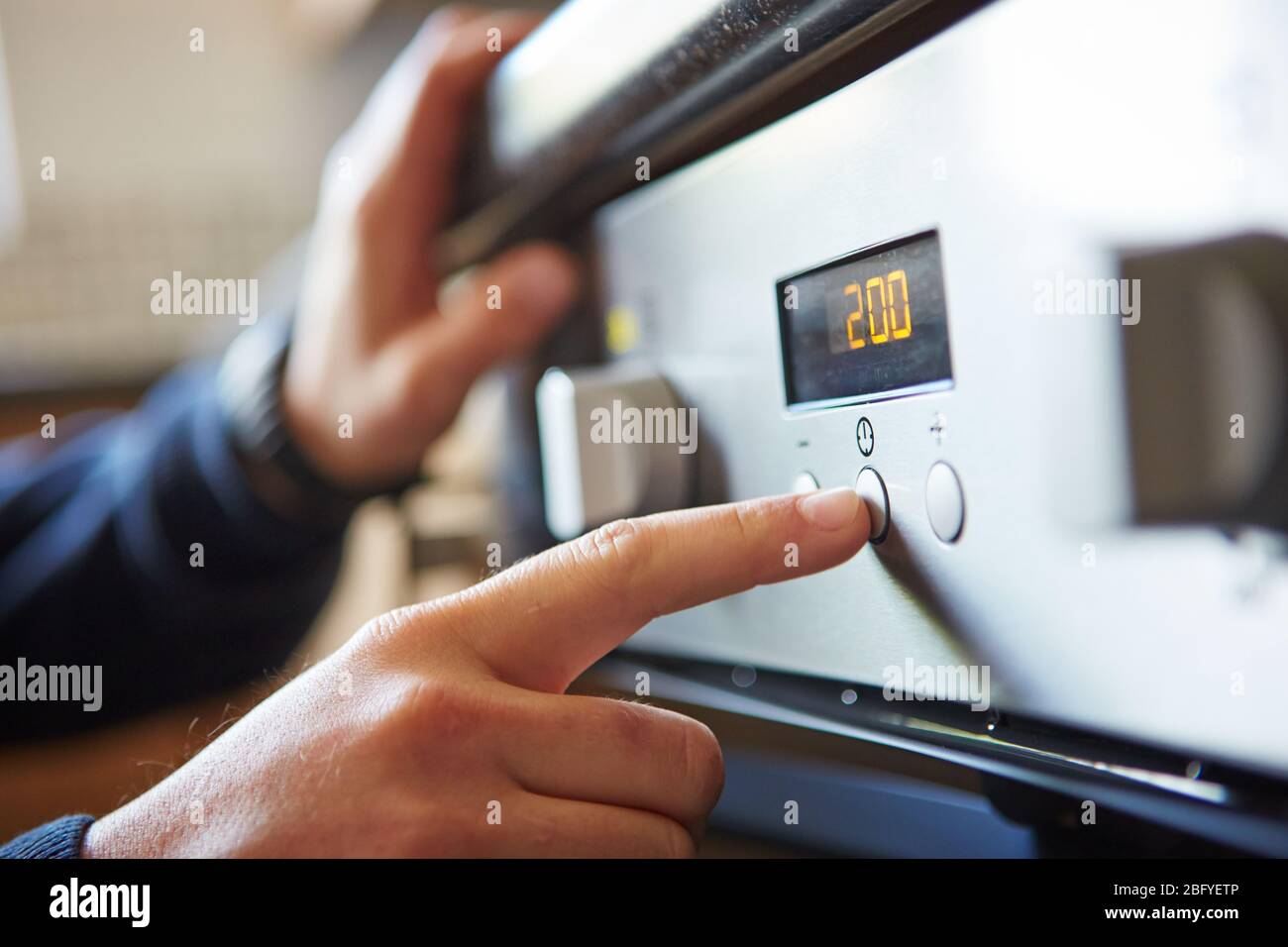 Close-up of a male hand starting a microwave oven for cooking food in kitchen at home, pushing a button. Stock Photo