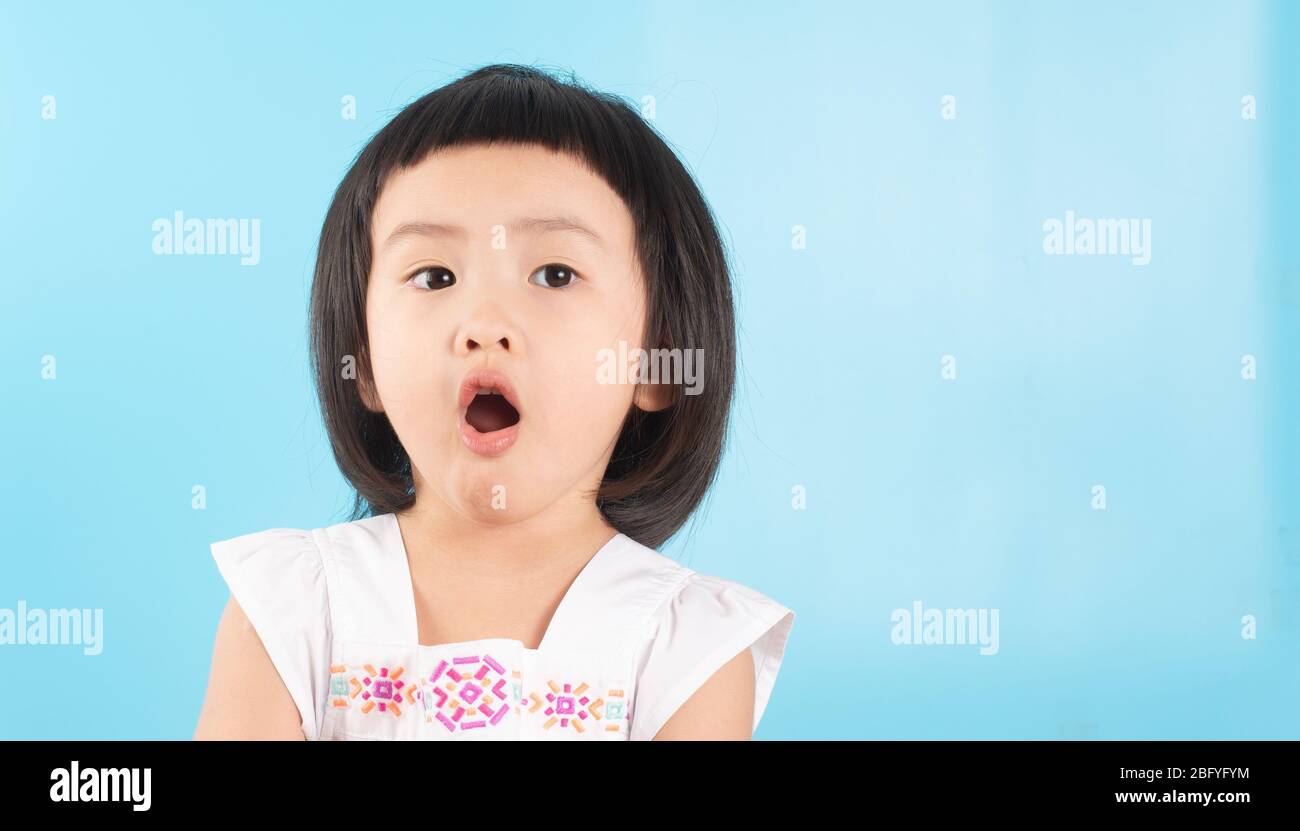 Cute Asian girls show off their faces. By surprise On a blue background and copy space. Stock Photo