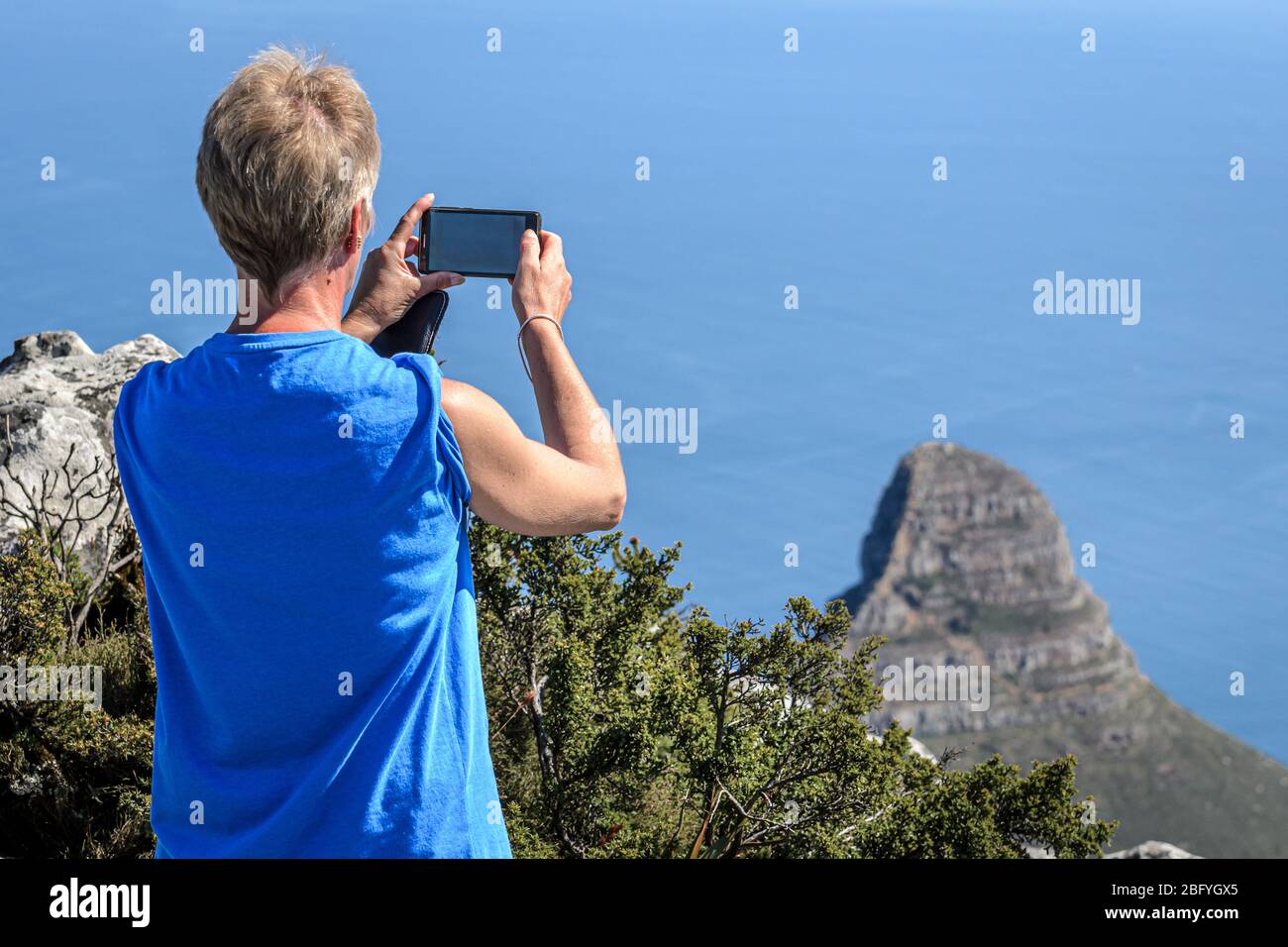 Caucasian woman tourist taking holiday snap with camera phone of Lions head from table mountain view point Cape Town south Africa Stock Photo