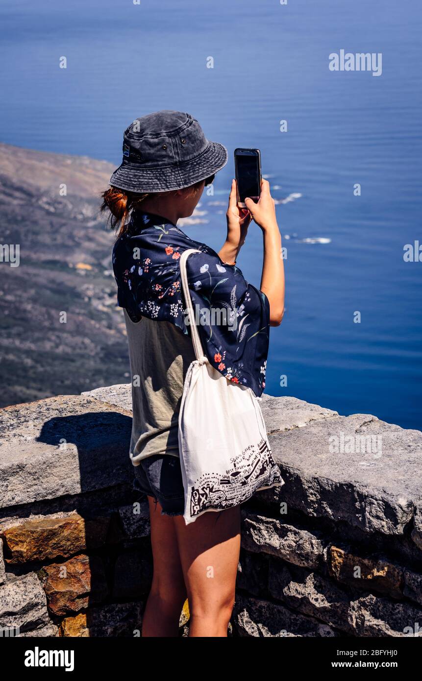 Young Asian tourist woman wearing sun hat taking photos from view point at Table Mountain Cape Town sout Africa Stock Photo