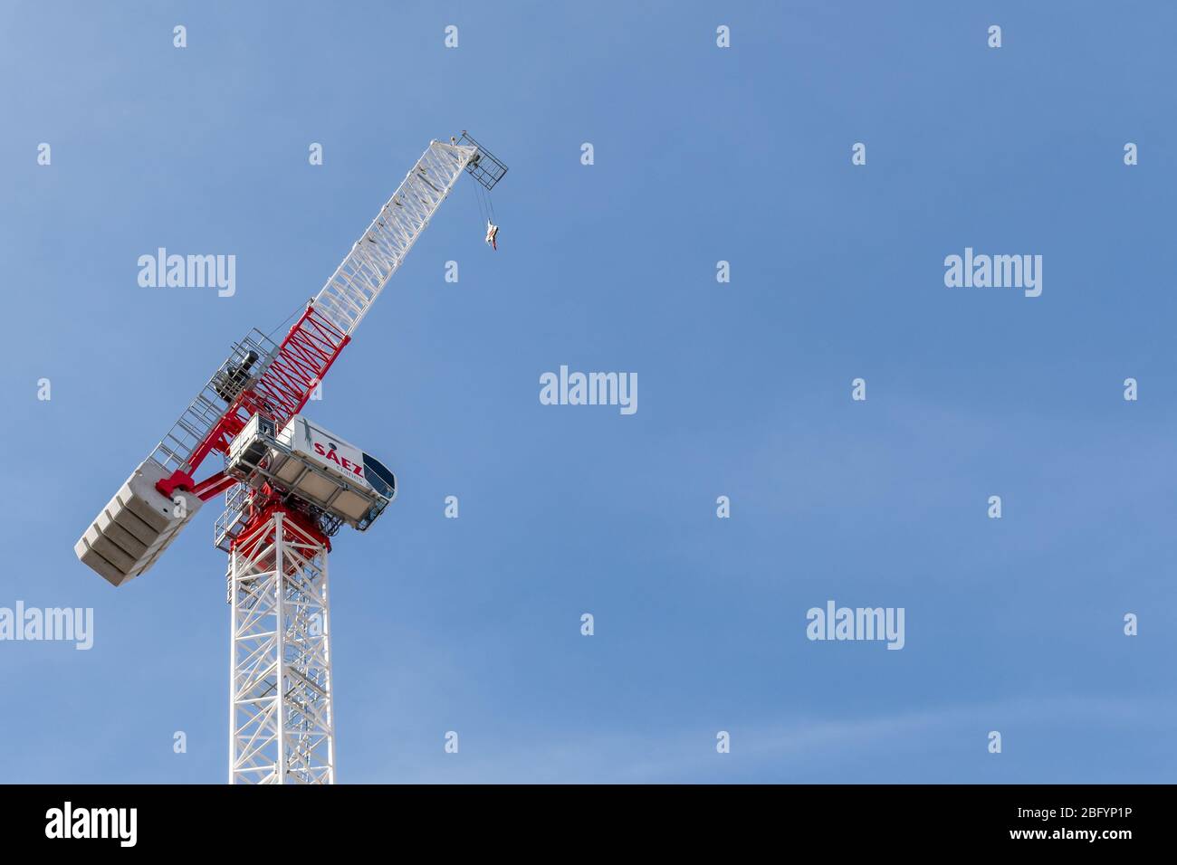 Red and white tower crane against a blue sky. Stock Photo