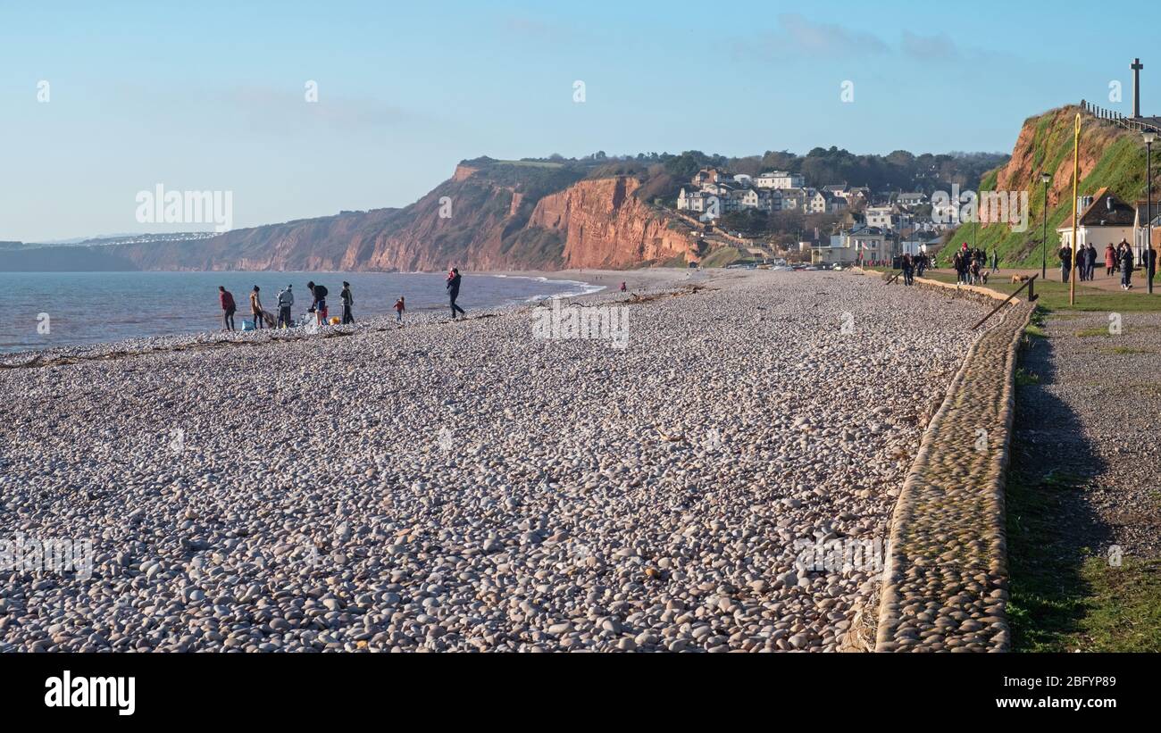 Budleigh Salterton, England – December 30, 2019: People taking advantage of winter sunshine on the pebble beach of this south east Devon coastal town Stock Photo
