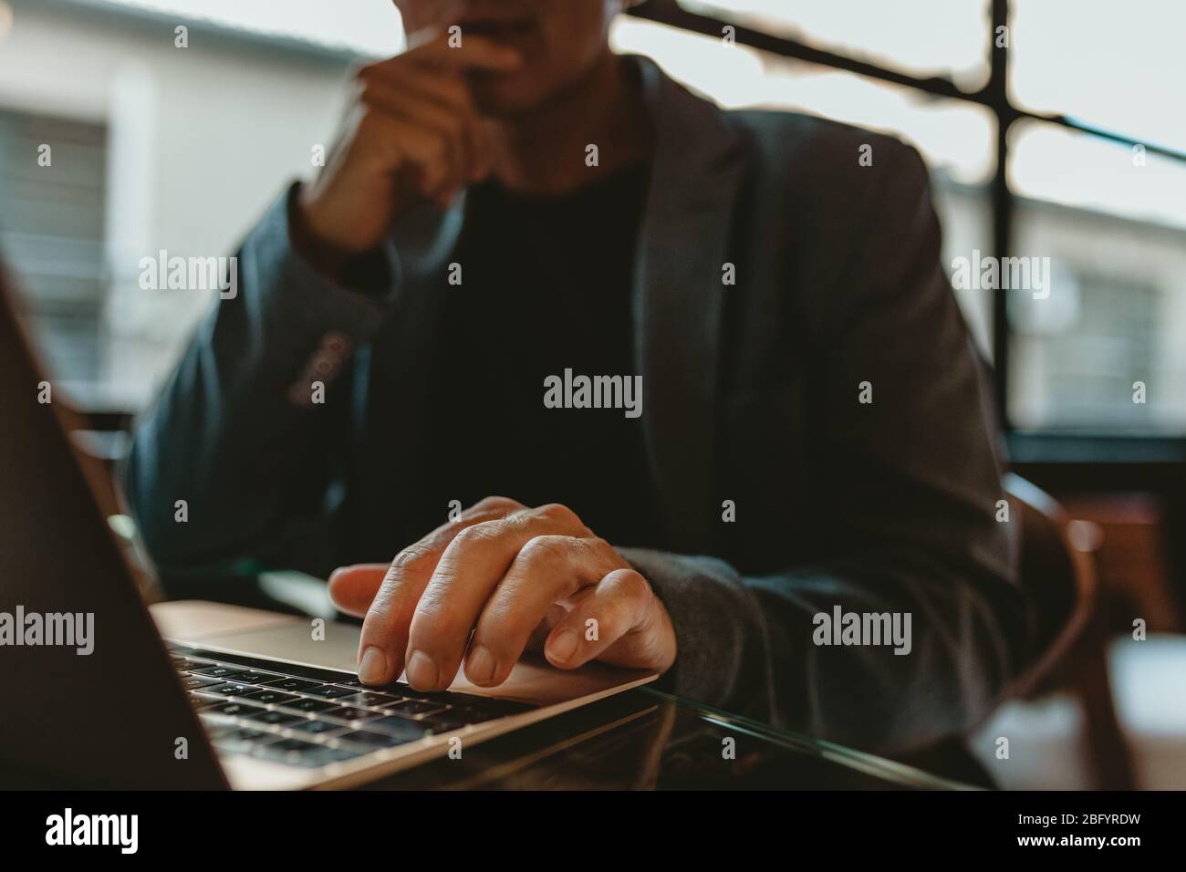 Close-up of a businessman working on laptop. Hand of a male executive working on laptop in office. Stock Photo