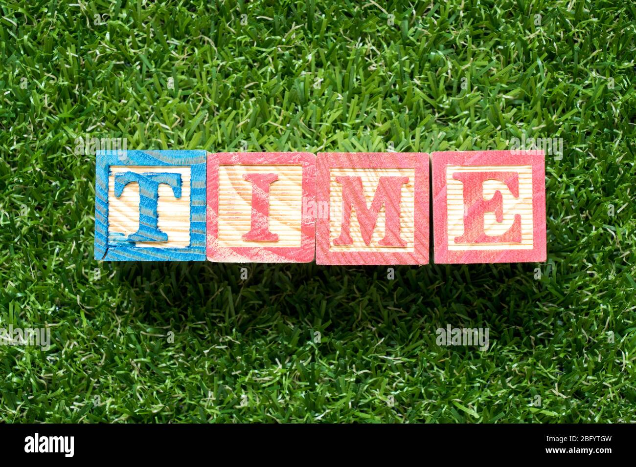 Color wood block in word time on artificial green grass background ...